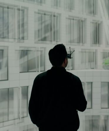 Man wearing VR-Glasses, standing infront of a window